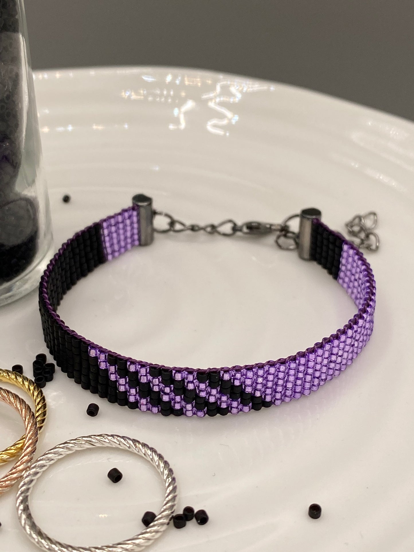 Purple and black beaded bracelet on a white surface with a gray background.
