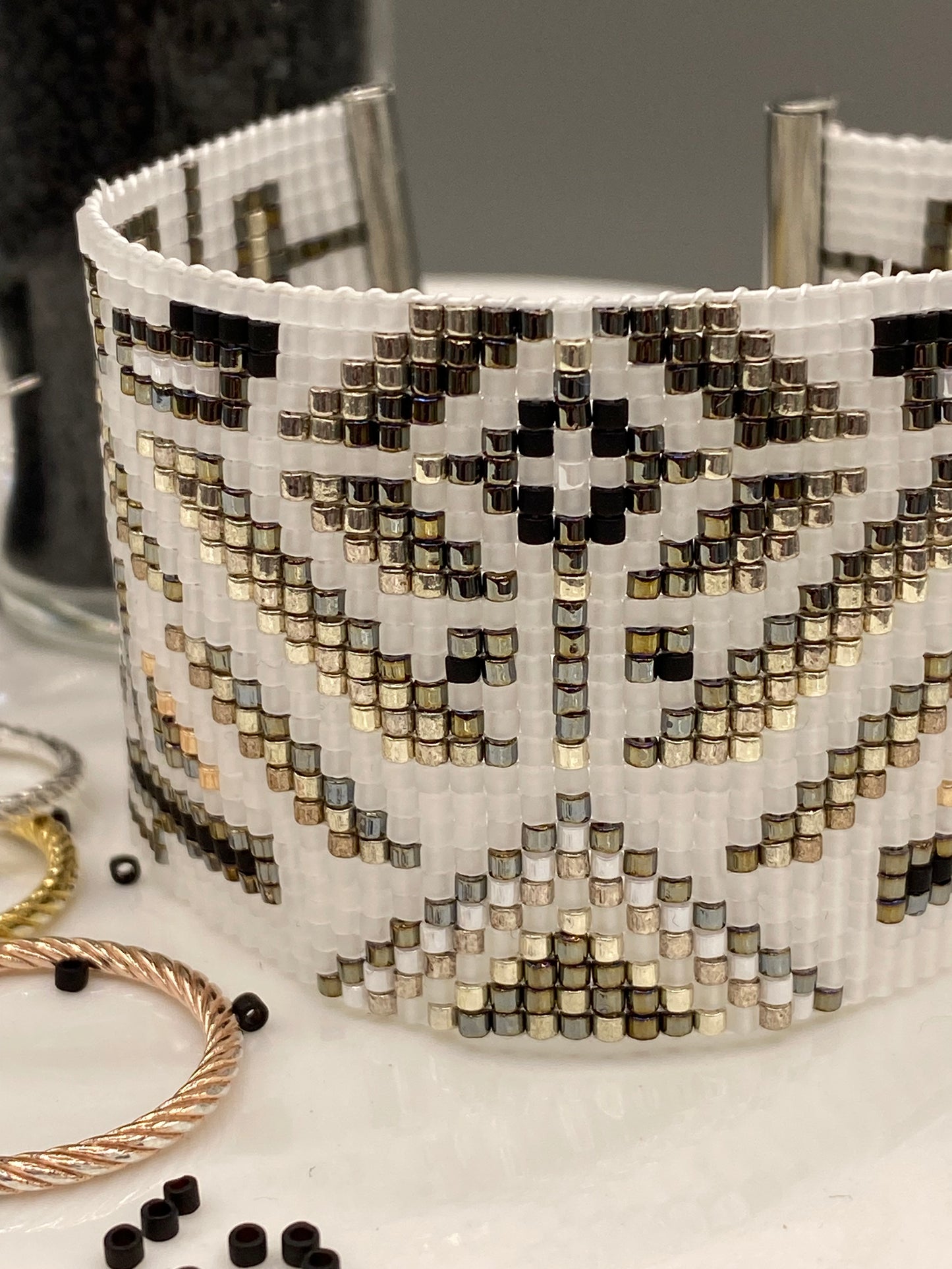 Close-up of a beaded cuff bracelet with intricate pattern on a white surface.