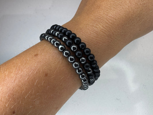 Black beaded bracelets on a wrist against a white background.