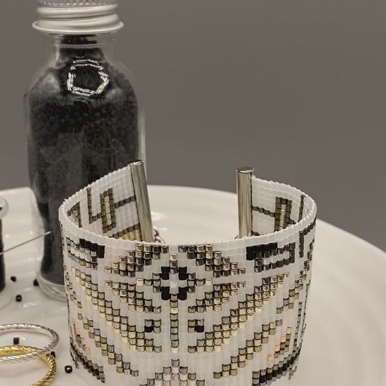 Video of a beaded cuff bracelet with intricate pattern on a white surface.