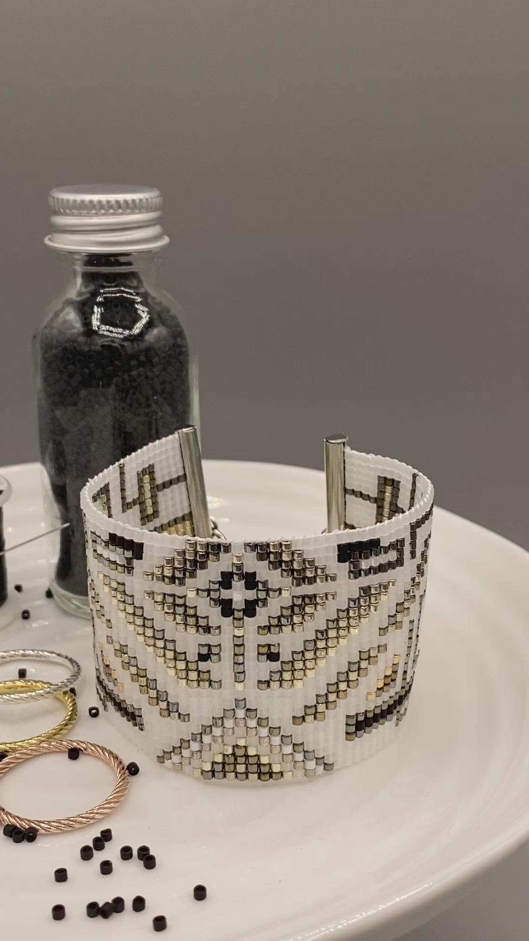 Video of a beaded cuff bracelet with intricate pattern on a white surface.